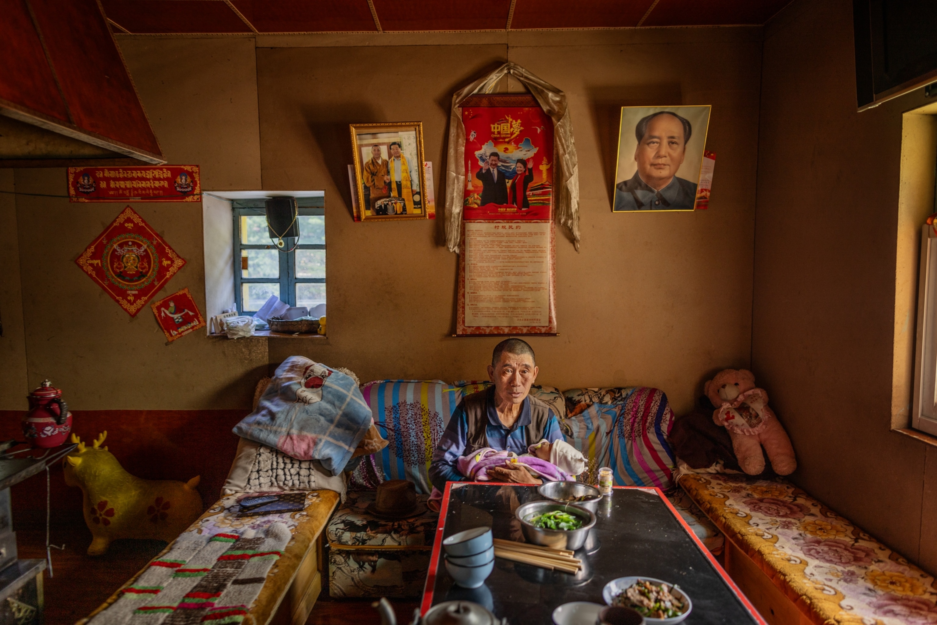 A grandfather holds his granddaughter at a dining table in their home