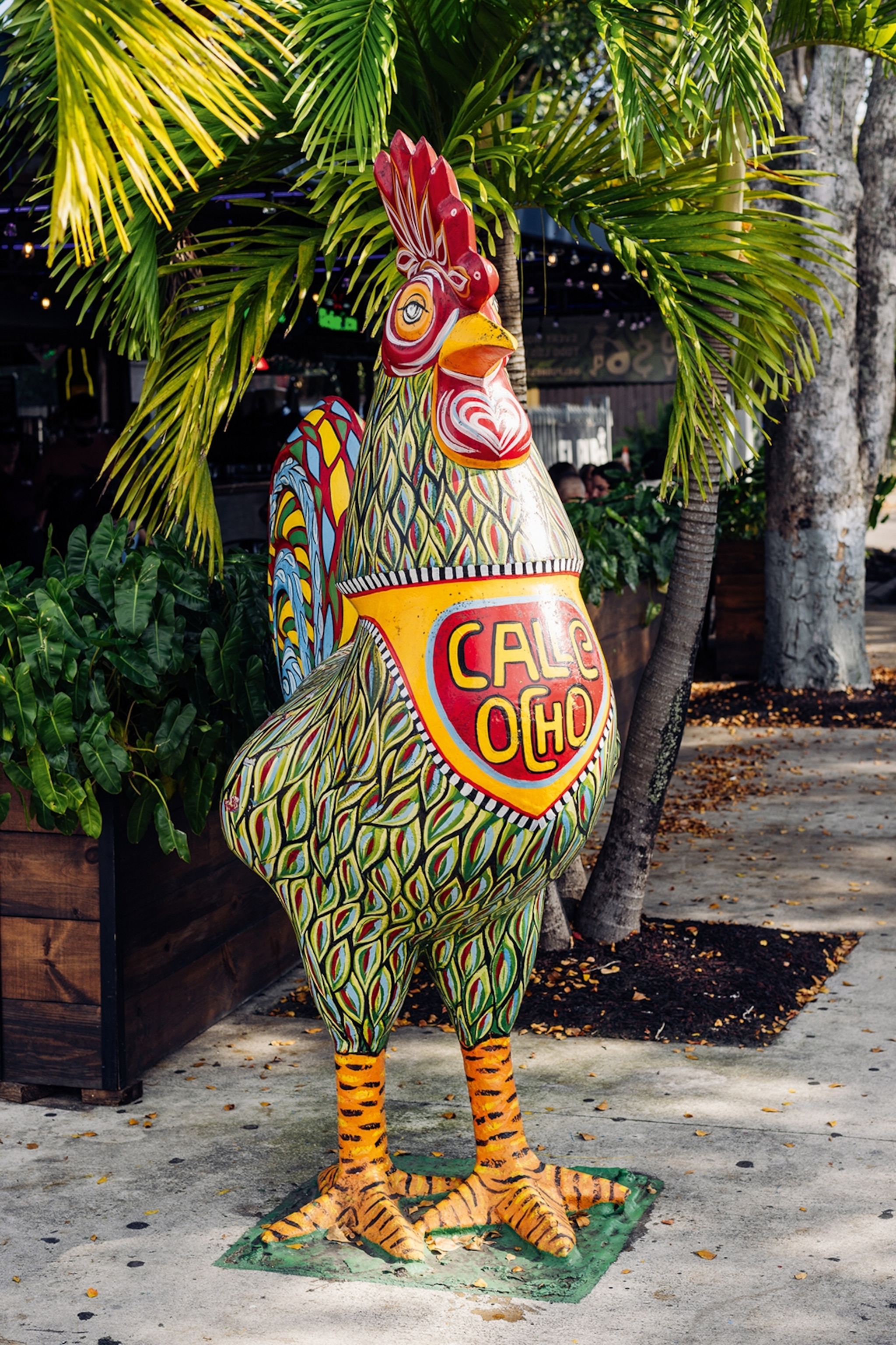 Colourfully painted cockerel ornament on a pavement reading 'Calle Ocho'