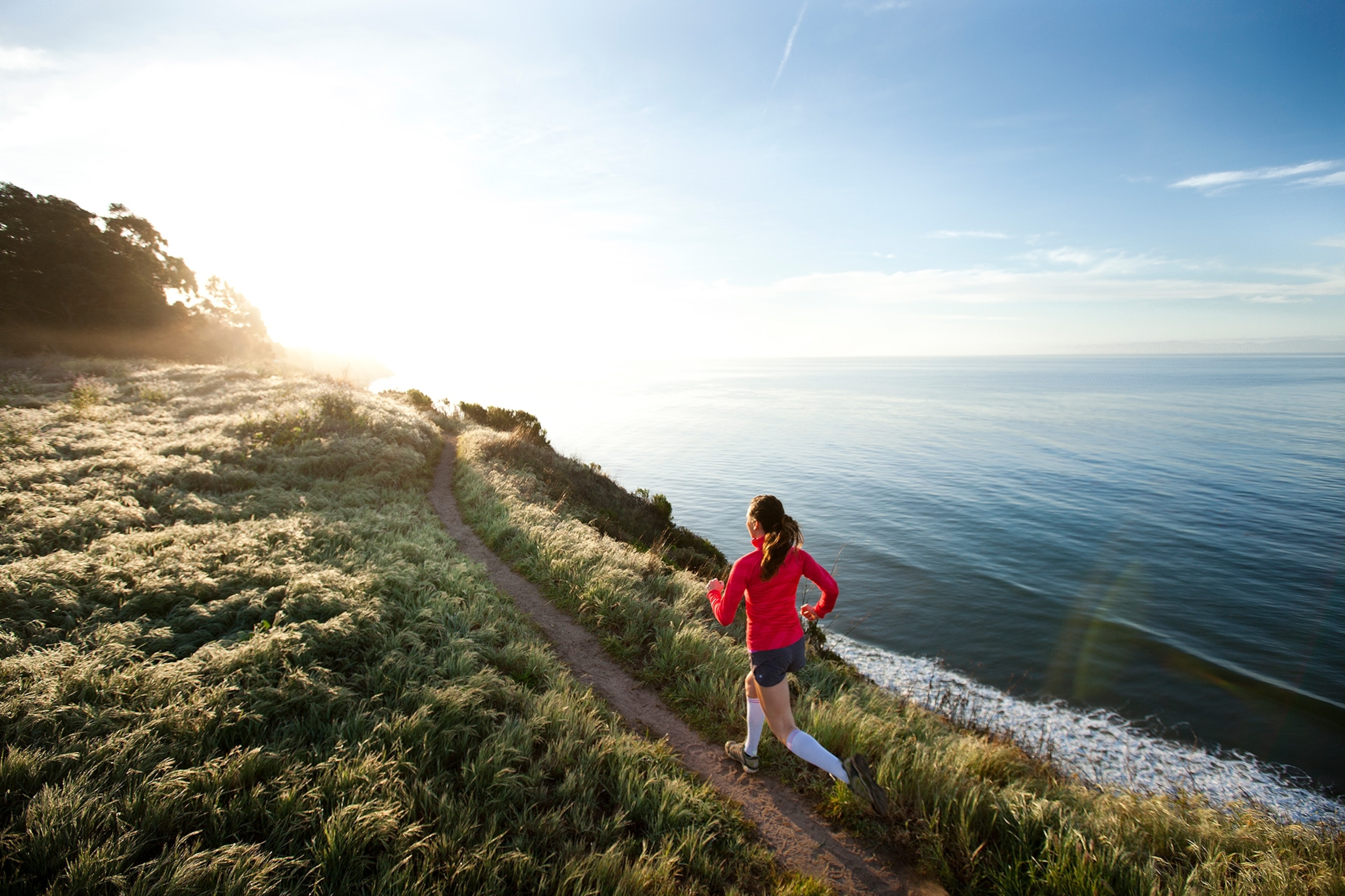 Woman trail running near the ocean.