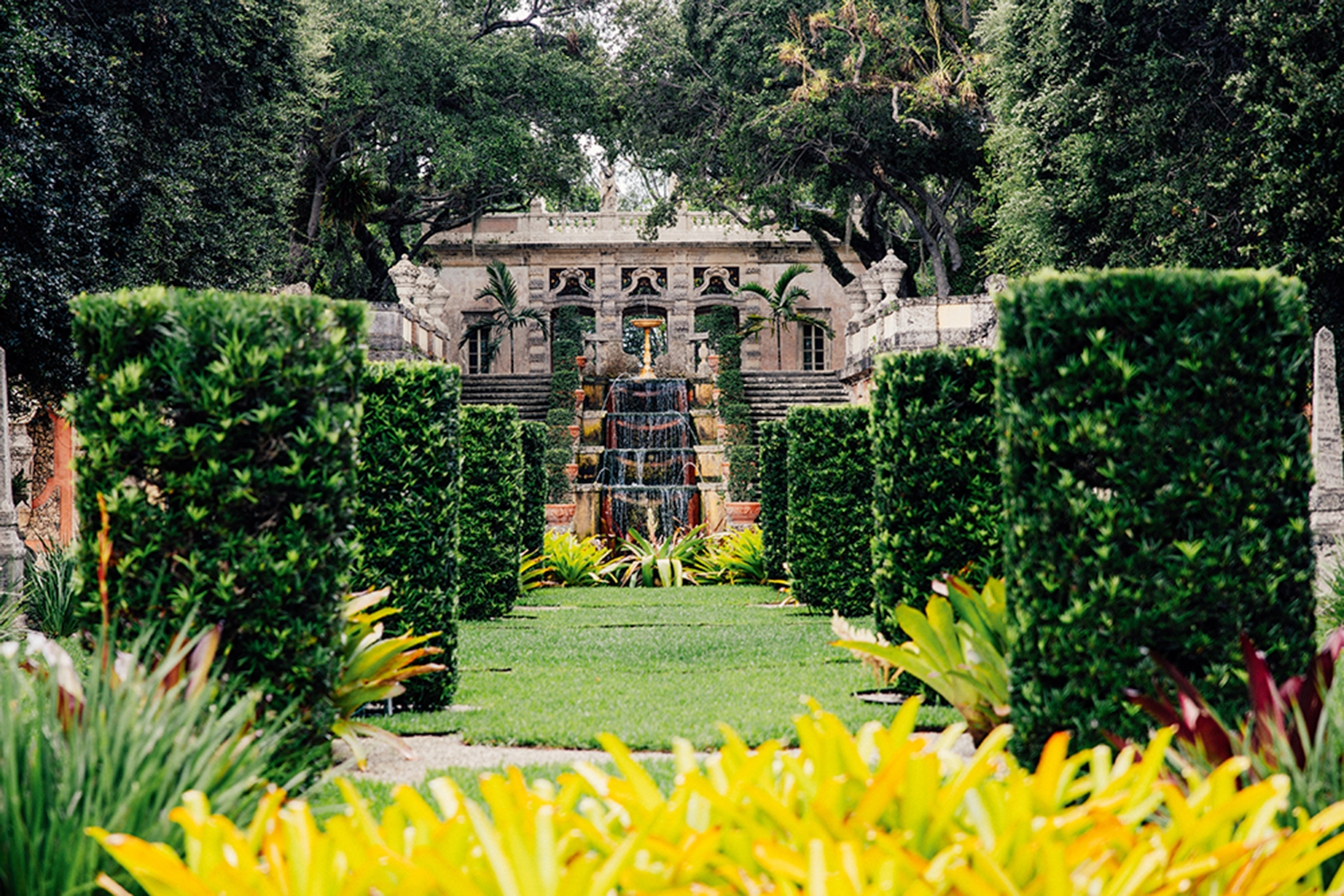 Gardens with green bushes with a fountain spurting water at the centre