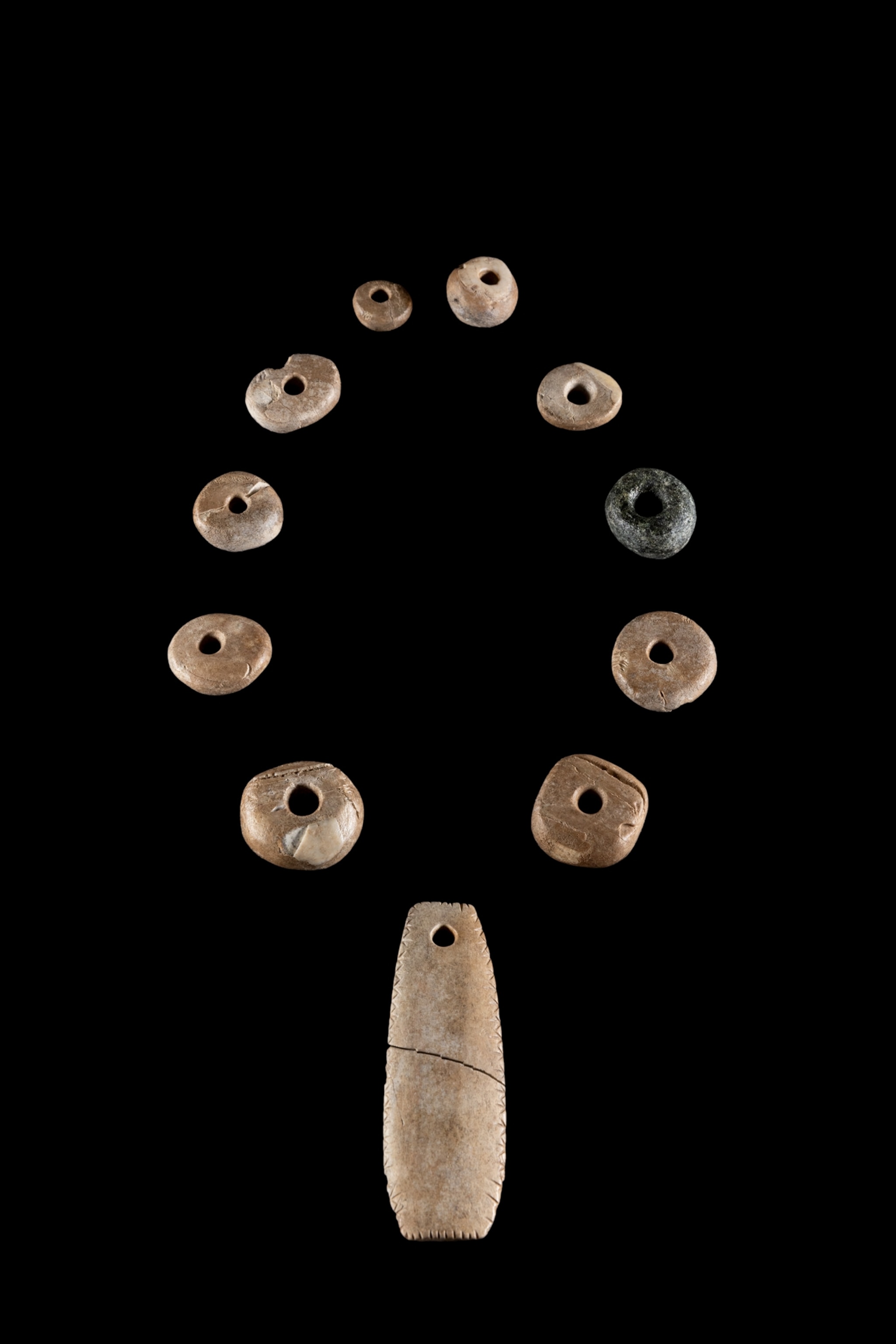 A neckalce includes one stone bead and nine beads and a pendant made from hippo ivory