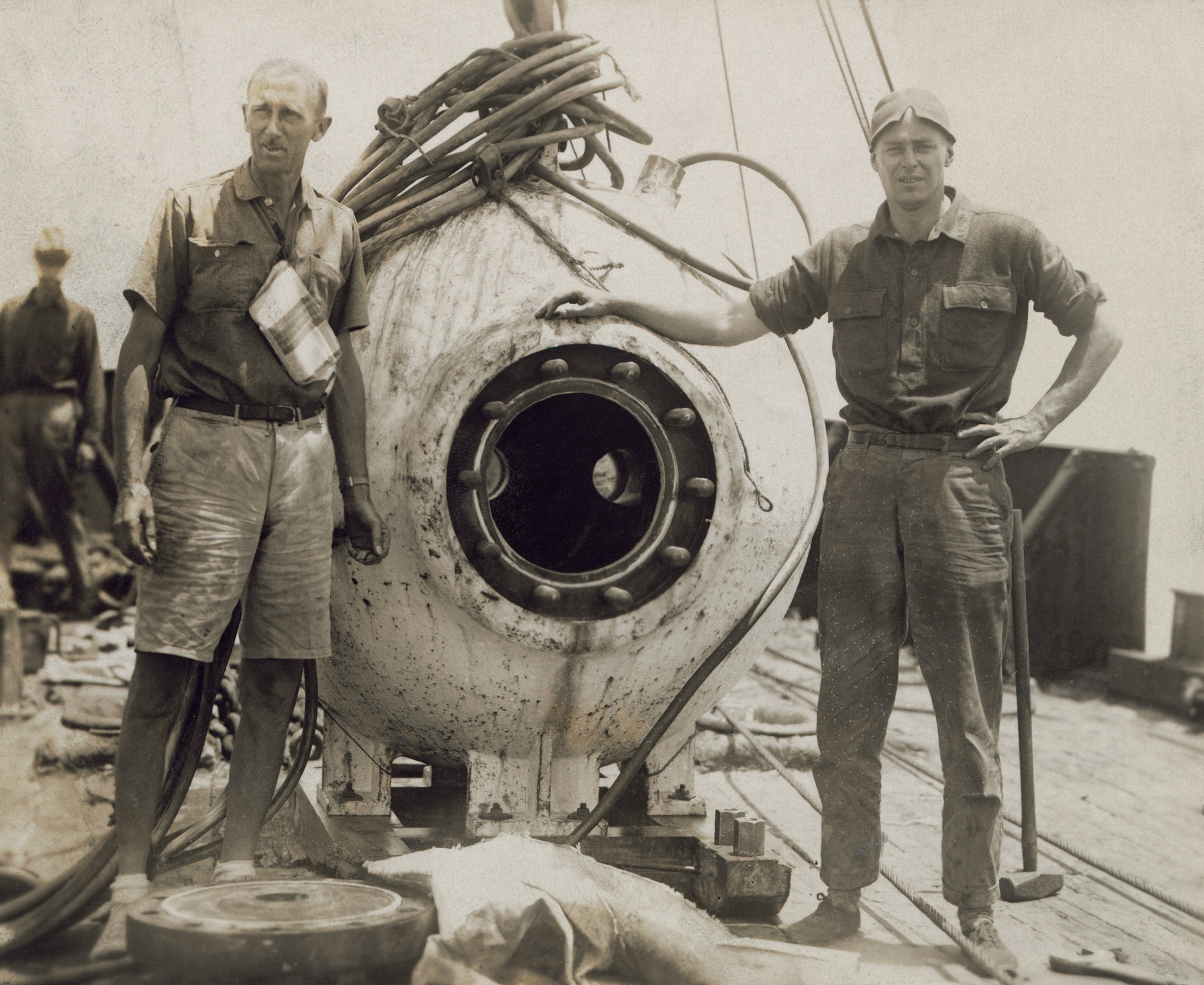 1934: Engineer Otis Barton and naturalist William Beebe stand next to the bathysphere